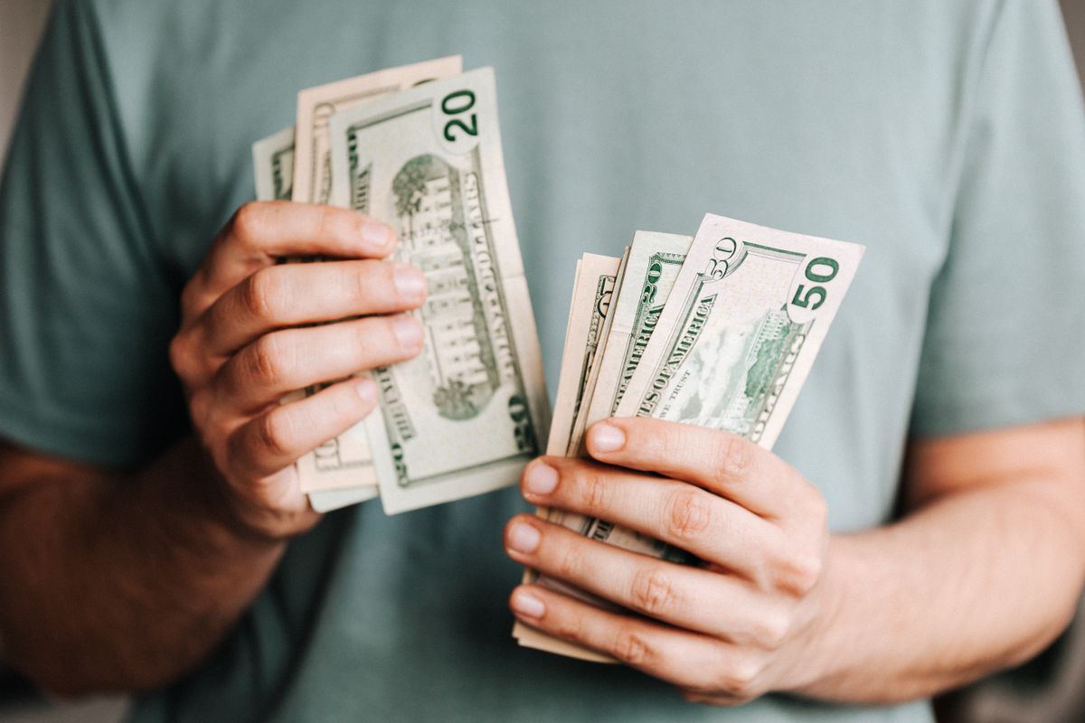 Hands holding cash for a mortgage down payment, checked with an online mortgage payment calculator